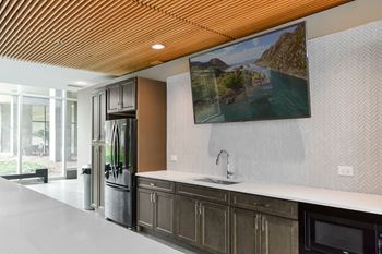 A modern kitchen with a wooden ceiling and a painting of a river on the wall.